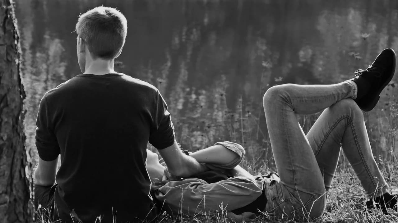 Deux adultes assis ensemble au bord d’un espace boisé